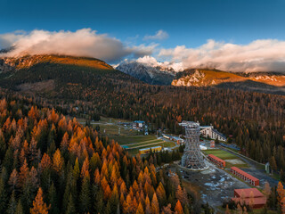 Strbske Pleso, Slovakia - Aerial view of the Strbske Lake area with autumn foliage, sightseeing tower and the High Tatras mountains at background on an autumn afternoon at sunset with warm sunlight