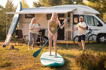 the family is resting next to their mobile home. My daughter is standing with a paddle on a sup...
