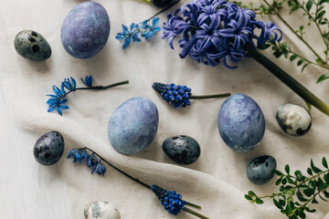 Easter flat lay. Stylish easter eggs and spring flowers on linen napkin on rustic table. Happy...