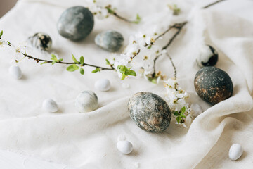 Happy Easter! Stylish easter eggs and spring flowers on linen rustic table. Natural painted marble...