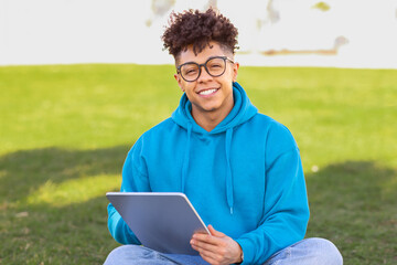 student guy in glasses surfing internet on digital tablet outdoor
