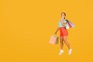 Positive young hispanic lady jumping with shopping bags