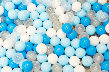 Colored plastic balls in pool of kindergarten school,White and blue plastic balls pit in game room,Many white balls background.