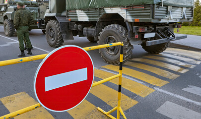 Armed soldiers standing near a roadblock with a no entry sign in the foreground. - obrazy, fototapety, plakaty