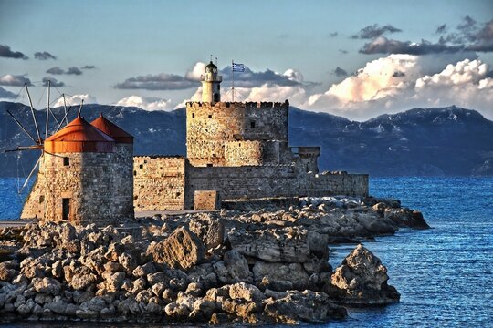 view of the blue sea, the remains of the fortress and the rocks above the sea from a distance where you can also see part of the settlement by the sea on a nice sunny day