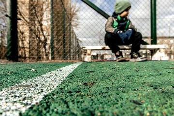 Artificial soccer field surface and blurred little boy in the background
