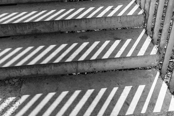 Shadow from iron railings on the concrete staircase. Striped shadow on gray steps