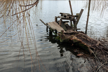 Fototapeta na wymiar Ugly fishing platform. Handmade bench on the shore of the lake for fishing