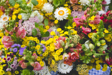 A background of a closeup of spring flower blossoms including feverfew, snapdragons, strawflower, ageratum and yarrow