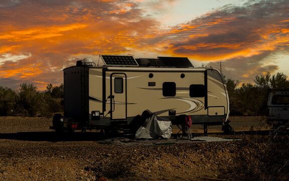 Rv trailer parked in open land area on self power with solar panels on roof 
