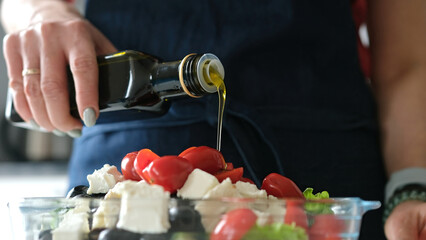 Female Hands Drizzle Oil On Greek Salad. Delicious Vegetarian Meal - 755111815