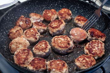 Cooking fried meatballs in a frying pan