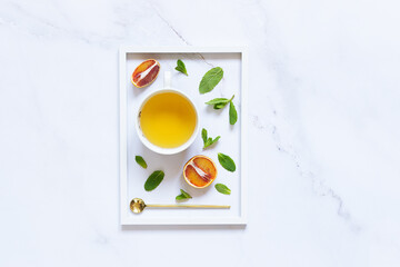 Fresh aromatic tea with ingredients on light marble background with white photo frame top view....