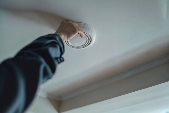 Hand installing fire alarm smoke detector in home