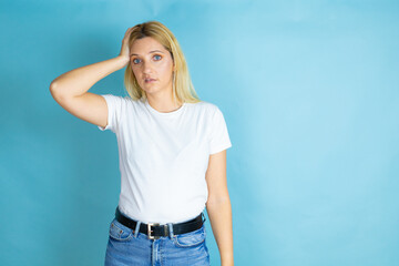 Young beautiful woman wearing casual t-shirt over isolated blue background putting one hand on her...