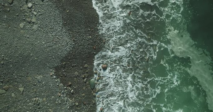 Plano cenital de la orilla con olas en una playa rocosa 