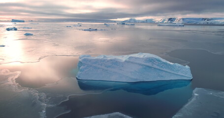 Blue glacier reflected in frozen ice ocean surface. Antarctica sunset landscape panorama. Huge ice...