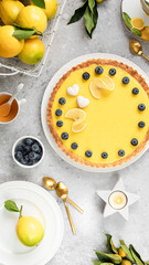 Traditional French lemon pie with blueberries on a white stone background. Vertical