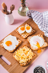 Eggs prepared to different recipes on toast on a wooden board vertical view