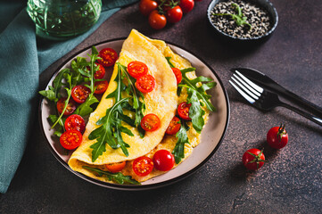 Omelette pancake with cherry tomatoes and arugula on a plate on the table