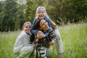 Beautiful mother with two daughters, embracing at meadow. Concept of Mother's Day, maternal love.