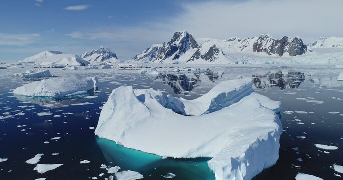 Close up polar seascape with iceberg at ocean bay aerial. Snow covered mountain at coast. Arctic melting fiord of ice. Global warming environment preservation. Cinematic climate change at Antarctica