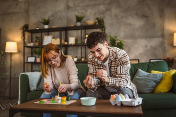 Naklejka premium young man and woman couple or brother and sister paint easter eggs