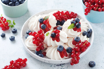 White sweet traditional merenques with berries on the plate