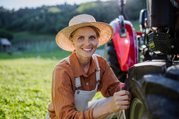 Female farmer fixing a wheel on a tractor. Progressive farmer working on tractor on her own farm....