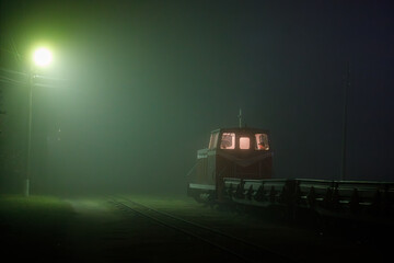 A shunting diesel locomotive moves along the rails. View of a shunting locomotive in the fog at night.