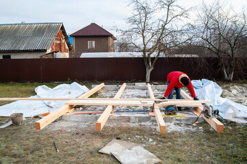 A man in a red jacket is engaged in construction using wooden planks - 755145460