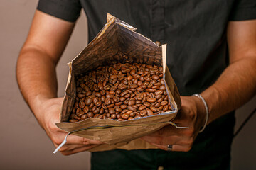 hombre sosteniendo una bolsa de cafe con grano en una cafeteria 