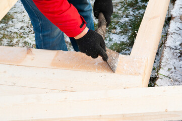 A man in a red jacket is engaged in construction using wooden planks - 755146208
