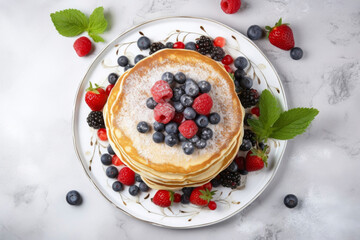 Plate with stack of pancakes with fresh strawberries, blueberries and raspberries and mint leaves, white marble table, top view