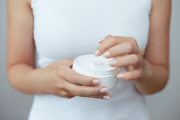 Closeup shot of woman hands holding cream and applying moisturizing hand cream. Beautiful female...