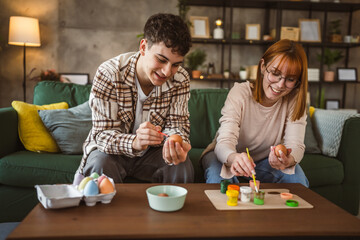 Fototapeta na wymiar young man and woman couple or brother and sister paint easter eggs