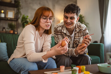young man and woman couple or brother and sister paint easter eggs