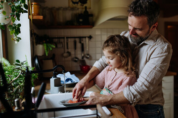 Dad and daughter washing dishes in sink together. Girls dad. Unconditional paternal love, Father's...