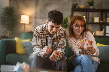 young man and woman couple or brother and sister paint easter eggs