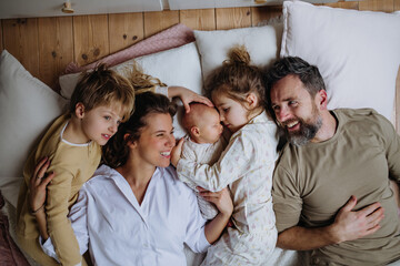 Top view of family lying in bed with kids and newborn baby. Perfect moment. Strong family, bonding and parents' unconditional love for their children.