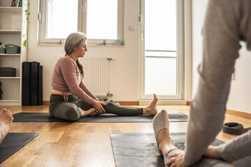 A small group of yoga students practices poses in a cozy studio, guided by their instructor's calm...