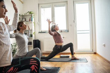 A small group of yoga students practices poses in a cozy studio, guided by their instructor's calm...