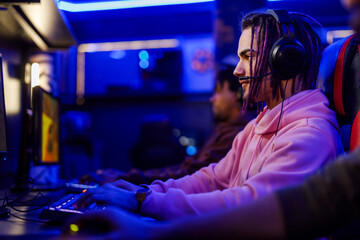 Concentrated young male with dreadlock playing video games in a an internet cafe