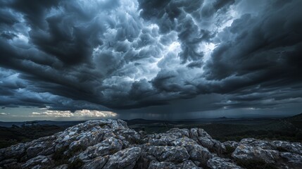 A dramatic sky with dark, rolling clouds over a rocky landscape, creating a mood of impending storm.