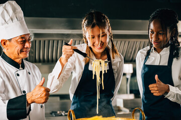 In kitchen chef coaches students. Schoolgirls prepare ramen. Kids and teacher at stove. Smiling...