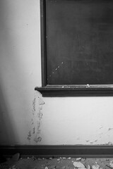 Demise of Education.  A worn-out blackboard hangs on a wall with peeling paint, showcasing signs of...
