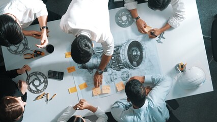 Top down aerial view of smart engineer team working together to design turbine engine. Professional...