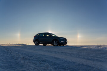 Fototapeta na wymiar Winter landscape with car and circular halo phenomena around the sun