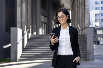 Confident young successful business woman standing outside an office center and courthouse, holding...