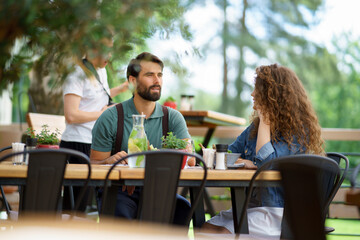 Young couple at date in restaurant, sitting on restaurant terrace. Boyfriend and girlfriend...